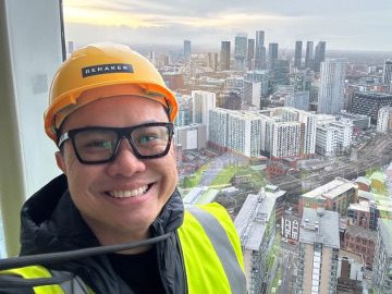 Joseph in a hard hat above the Manchester skyline